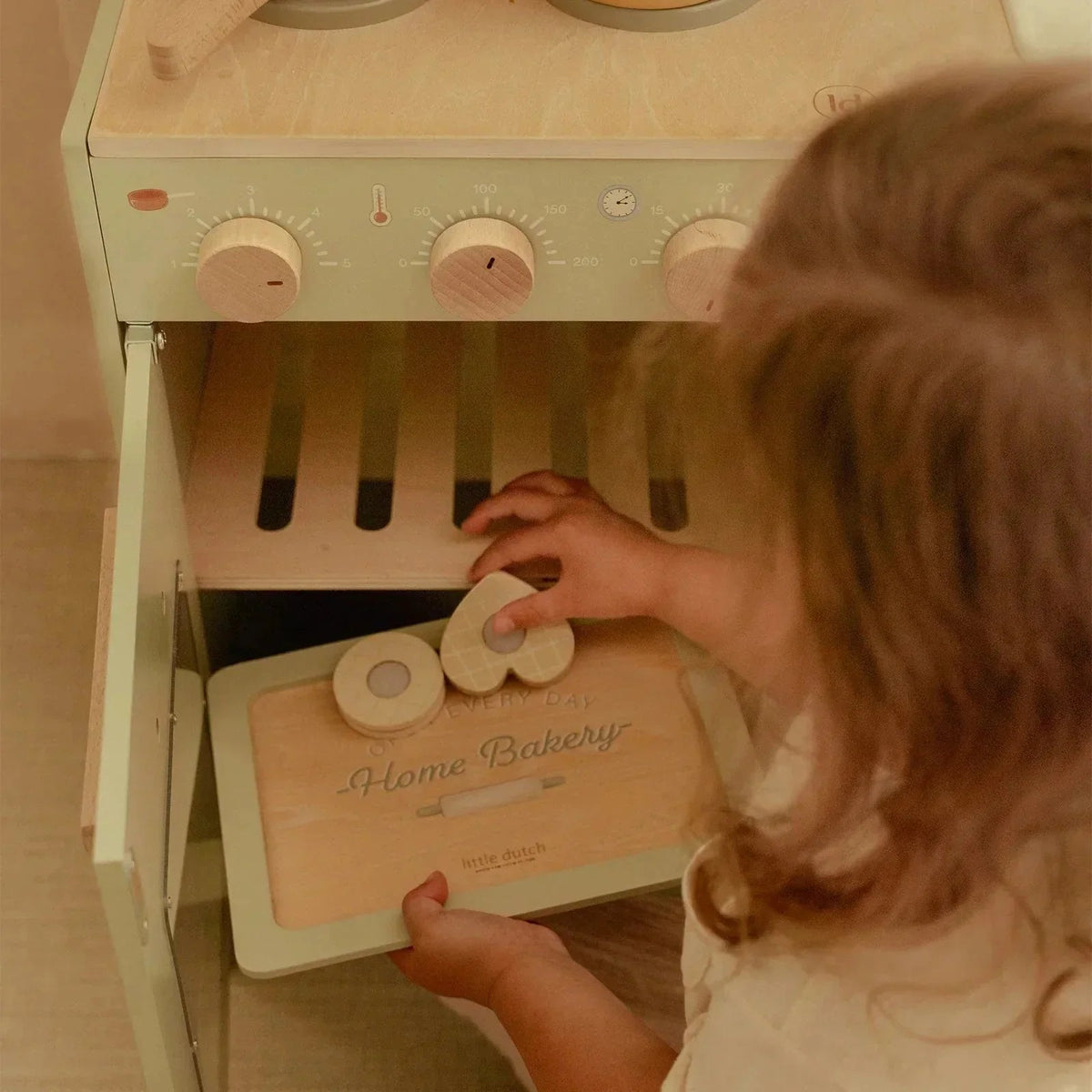 A child playing with a Little Dutch wooden toy baking set and play oven.