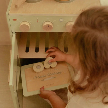 A child playing with a Little Dutch wooden toy baking set and play oven.