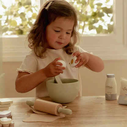 Toddler playing with Little Dutch baking set including a wooden rolling pin and bowl.