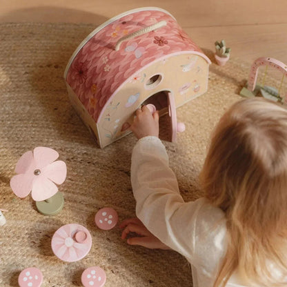 A child playing with a Little Dutch Fairy House and garden toy set on a rug.