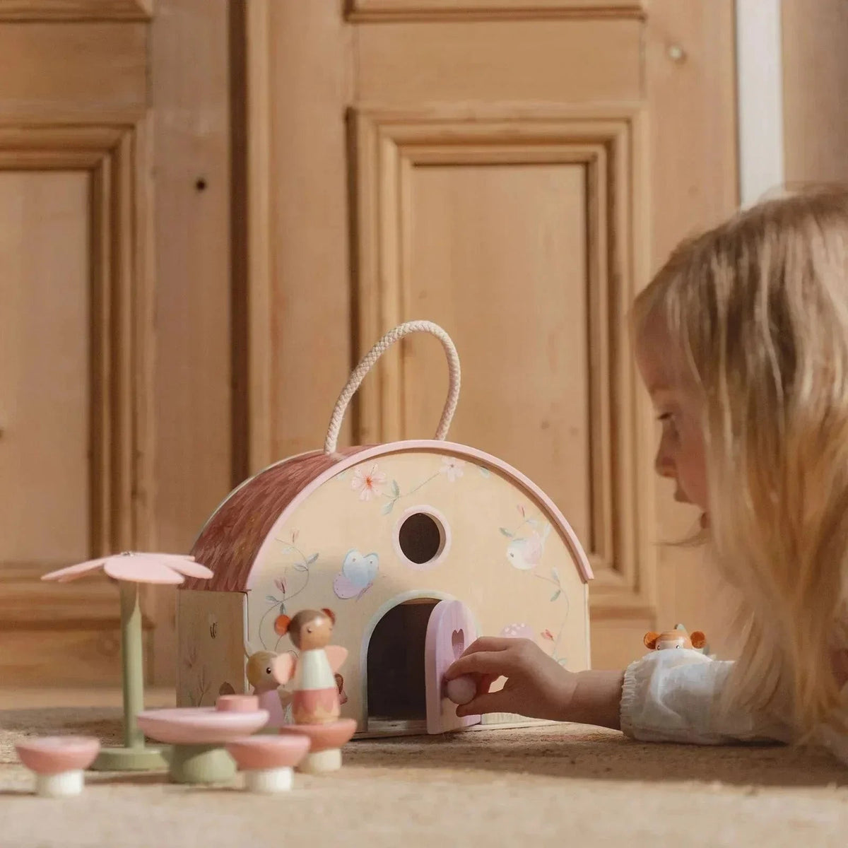 A child playing with a Little Dutch Fairy House & Garden wooden toy set.
