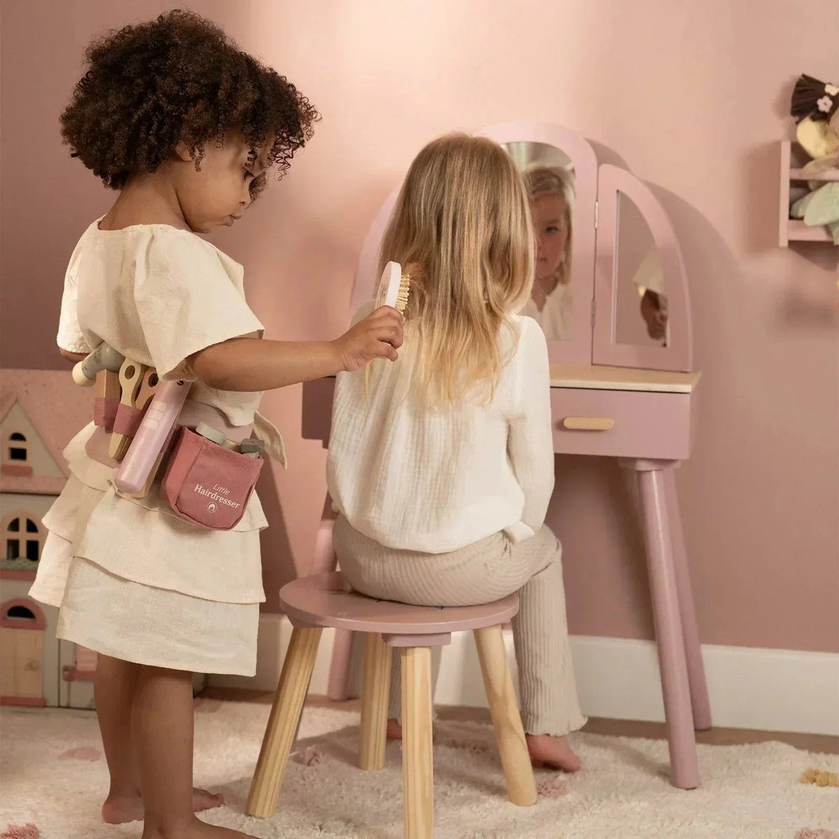 Child using a Grayskull Toys Little Dutch Hairdresser Set to brush another child's hair.