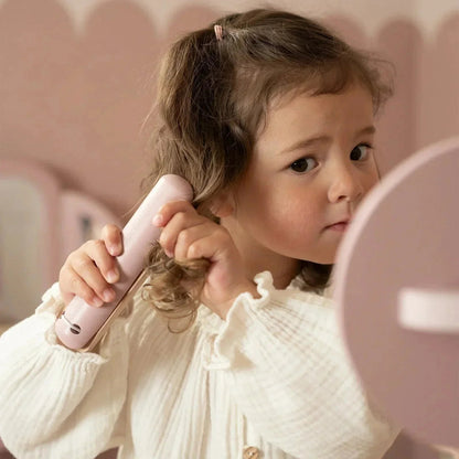 A young girl playing with a pink Grayskull Toys toy hair dryer on her curly hair.