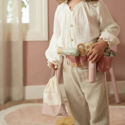Child wearing a Grayskull Toys Little Dutch hairdresser set tool belt and holding a drawstring bag.
