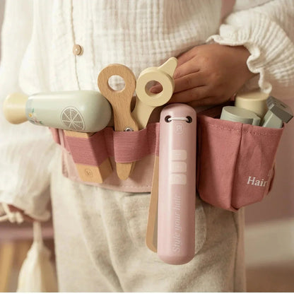 Child wearing a Grayskull Toys Little Dutch Hairdresser Set tool belt with wooden accessories.