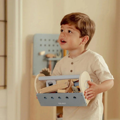 A young child holding a Grayskull Toys wooden toy tool box with various play tools inside.